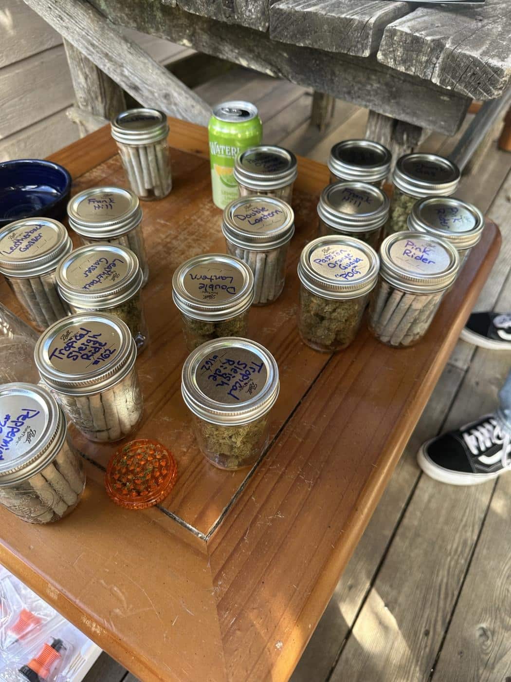 Gläser mit Blüten und gedrehte Joints auf einem Holztisch